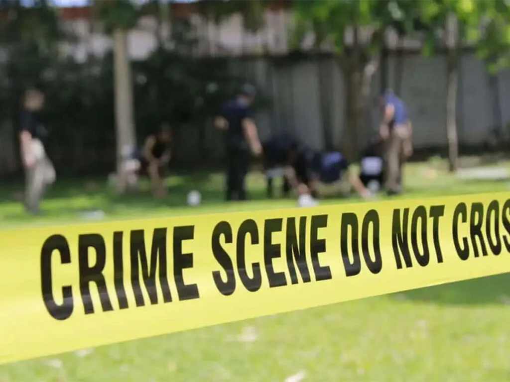 crime scene tape with police officers in the background